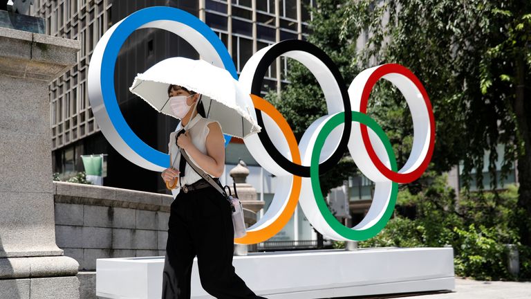 A woman walks past the Olympics rings in Tokyo