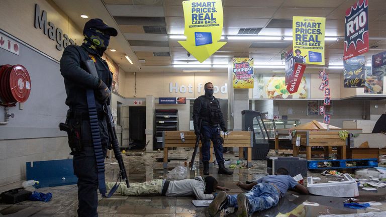 Police stand over detained suspected looters in a shopping centre in Alexandra township, Johannesburg