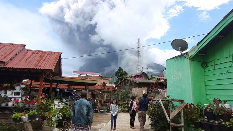Lidé sledují, jak hora Sinabung chrlí sopečný materiál během sopečné erupce v Karu na severní Sumatře v Indonésii.  Středa 28. července 2021. Sinabung je jedním z více než 120 aktivních vulkánů v Indonésii, které jsou díky poloze v Tichém oceánu náchylné k seismickým poruchám. "ohnivý kruh," Oblouk sopek a zlomových linií, které obklopují Pacifickou pánev (AP Photo/Sastrawan Ginting)