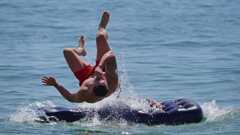 A man jumps off an inflatable lilo off Bournemouth beach in Dorset. England could see the hottest day of the year this weekend as the skies finally clear after weeks of wet and humid weather. Picture date: Saturday July 17, 2021.

