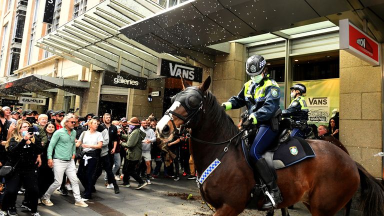 Protesters throw plastic bottles and pot plants at mounted police in the city centre during an anti-lockdown rally as an outbreak of the coronavirus disease (COVID-19) affects Sydney, Australia, July 24, 2021. AAP Image/Mick Tsikas via REUTERS ATTENTION EDITORS - THIS IMAGE WAS PROVIDED BY A THIRD PARTY. NO RESALES. NO ARCHIVE. AUSTRALIA OUT. NEW ZEALAND OUT