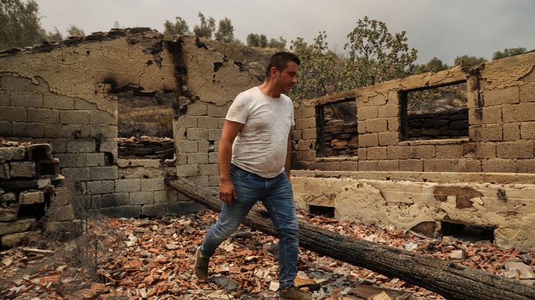 Un cittadino cammina tra le rovine di una casa bruciata in un'area bruciata da un incendio boschivo vicino alla città di Manavgat, a est della città turistica di Antalya, in Turchia, 29 luglio 2021. REUTERS/KAN Sweyturk