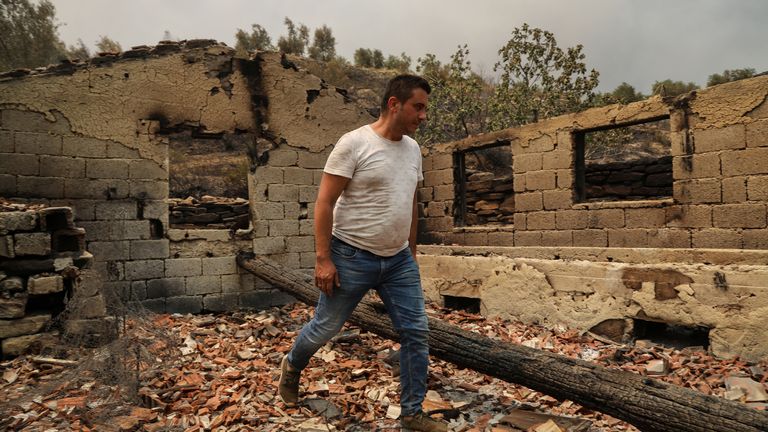 A resident walks in the remains of a burnt house in an area scorched by a forest fire near the town of Manavgat, east of the resort city of Antalya, Turkey, July 29, 2021. REUTERS/Kaan Soyturk
