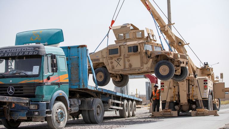 U.S. Army soldiers and contractors load High Mobility Multi-purposed Wheeled Vehicles, HUMVs, to be sent for transport as U.S. forces prepare for withdrawal
