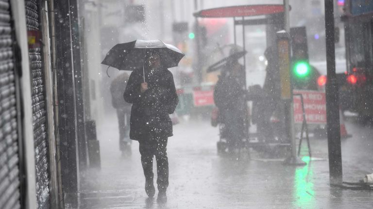 A man walking in a rain shower in east London