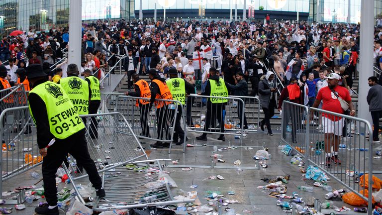 Stewards replace barricades after they were knocked over by supporters outside Wembley Stadium in London, Sunday, July 11, 2021, during the Euro 2020 soccer championship final match between England and Italy. (AP Photo/David Cliff)