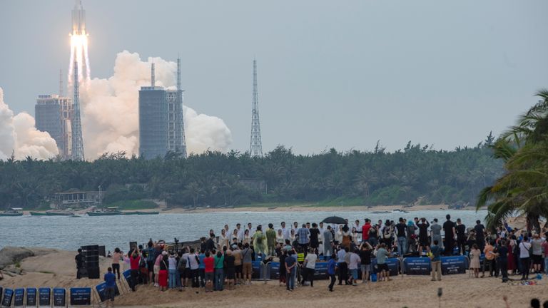 People watch from a beach as the Long March-5B Y2 rocket, carrying the core module of China&#39;s space station Tianhe, takes off from Wenchang Space Launch Center in Hainan province, China April 29, 2021