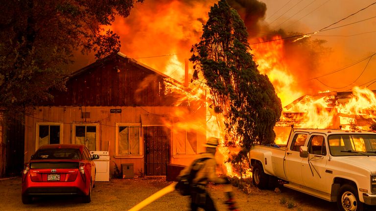 A blaze consumes a home as the Sugar Fire, part of the Beckwourth Complex Fire, rages in California