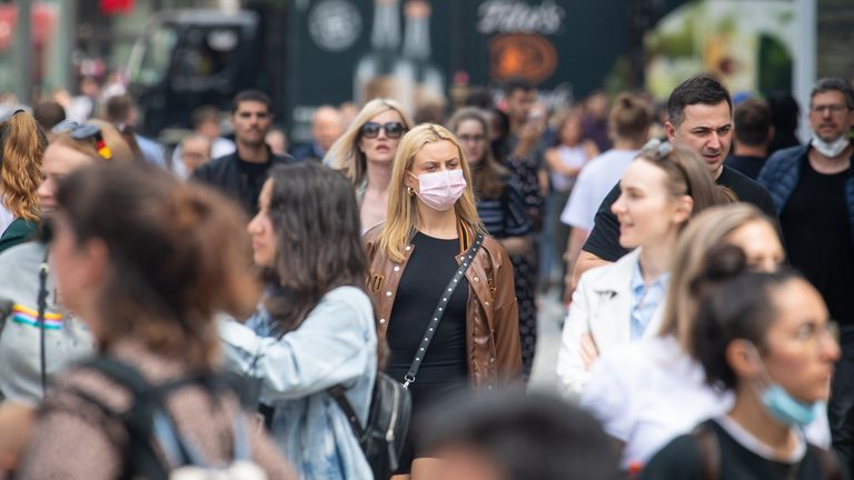 A woman wears a face mask among a crowd of pedestrians on Oxford Street, London
