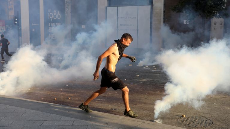 A demonstrator runs amid smoke rising from tear gas during a protest near parliament, as Lebanon marks the one-year anniversary of the explosion in Beirut, Lebanon August 4, 2021. REUTERS/Mohamed Azakir