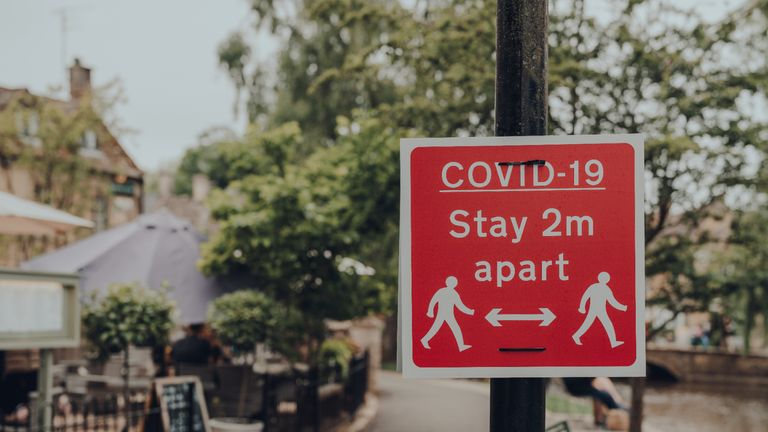 Red Covid-19 Stay 2 Metres Apart sign on a sidewalk in Bourton-on-Water, Cotswolds, UK, during COVID 19 pandemic. Selective focus.