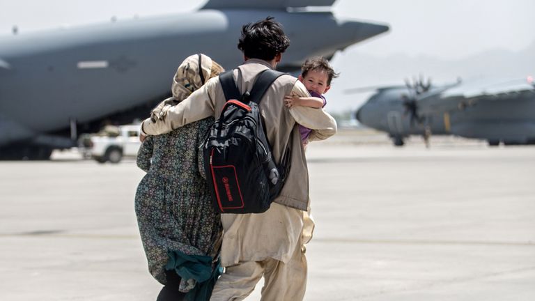 A family walks towards a U.S. Air Force Boeing C-17 Globemaster III during an evacuation at Hamid Karzai International Airport, Afghanistan, August 22, 2021. Picture taken August 22, 2021.  U.S. Marine Corps/Sgt. Samuel Ruiz/Handout via REUTERS.  THIS IMAGE HAS BEEN SUPPLIED BY A THIRD PARTY. THIS PICTURE WAS PROCESSED BY REUTERS TO ENHANCE QUALITY. AN UNPROCESSED VERSION HAS BEEN PROVIDED SEPARATELY.