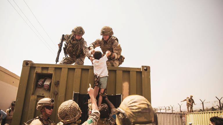 UK coalition forces, Turkish coalition forces, and U.S. Marines assist a child during an evacuation at Hamid Karzai International Airport, Kabul, Afghanistan, in this photo taken on August 20, 2021.  Sgt. Victor Mancilla/U.S. Marine Corps/Handout via REUTERS THIS IMAGE HAS BEEN SUPPLIED BY A THIRD PARTY.     TPX IMAGES OF THE DAY