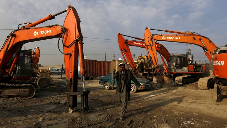 A man walks next to machinery parked at the Omid Gardizi construction company in Kabul, Afghanistan November 30, 2015.