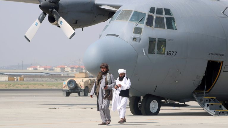 A tálibok katonai repülőgép előtt sétálnak egy nappal azután, hogy az amerikai csapatok kivonultak az afganisztáni Kabul Hamid Karzai nemzetközi repülőtérről