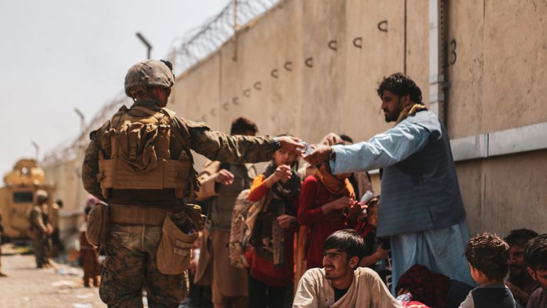 A US Marine passes out water to evacuees at Kabul&#39;s international airport