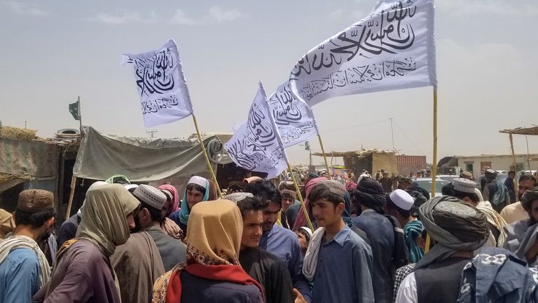 Des personnes portant des drapeaux talibans se rassemblent pour accueillir un homme (non représenté) qui a été libéré de prison en Afghanistan, à son arrivée au point de passage de Friendship Gate dans la ville frontalière pakistano-afghane de Chaman, Pakistan, le 16 août 2021. REUTERS/Saeed Ali Achakzai