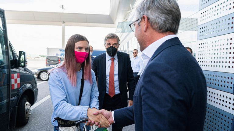 Belarusian Sprinter Krystsina Tsimanouskaya shakes hands with Austrian State Secretary Magnus Brunner during a stop at Schwechat airport in Vienna, Austria