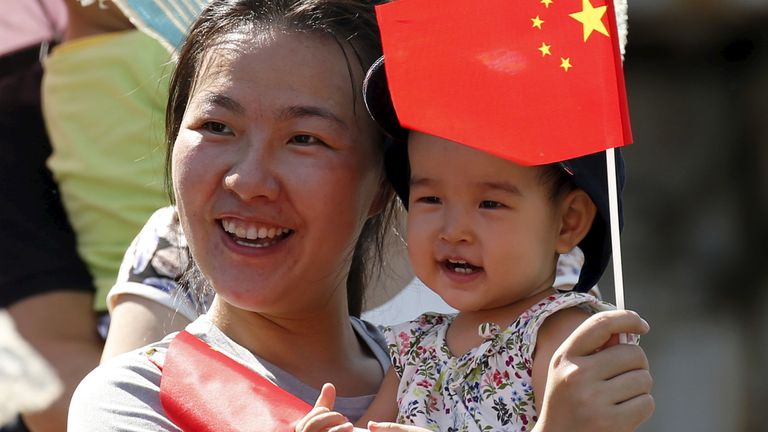 A woman and her baby wait on the street for the performance of military helicopters and planes during the military parade marking the 70th anniversary of the end of World War Two, in Beijing, China, September 3, 2015. REUTERS/Kim Kyung-Hoon