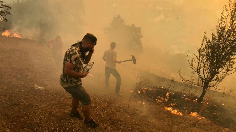 Villagers attempt to put out the flames of a wildfire in the mountainous Kabylie region of Tizi Ouzou, east of Algiers, Algeria 