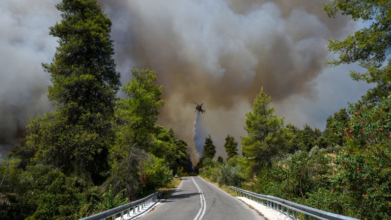A firefighting helicopter makes a water drop as a wildfire burnson the island of Evia