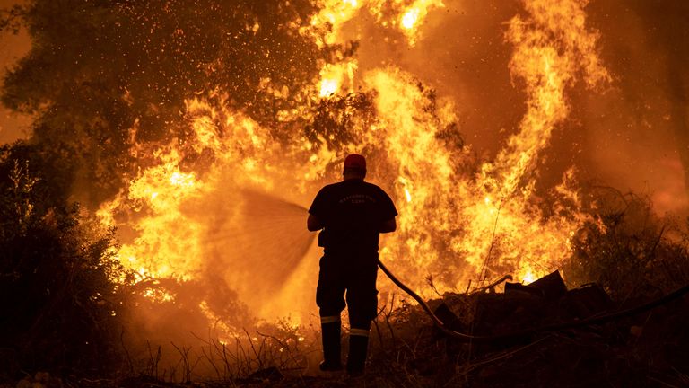 A firefighter tries to extinguish a wildfire burning in the village of Pefki, on the island of Evia, Greece, August 8, 2021. REUTERS/Nikolas Economou
