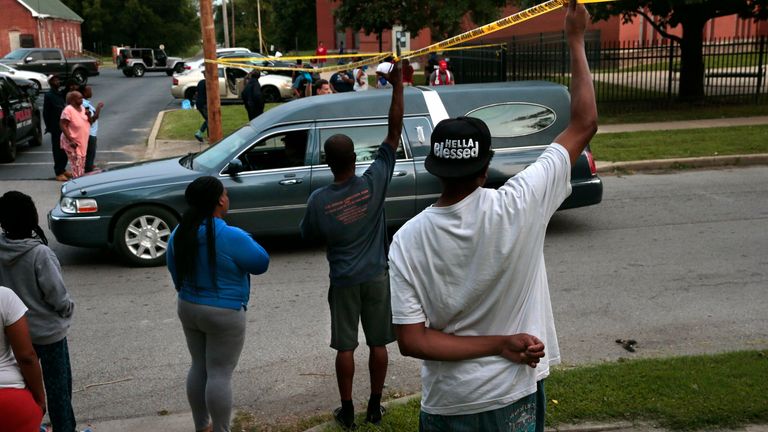 Kenneth Jennings, right, helps hold crime scene tape as a hearse carrying the remains of children leaves the scene of an East St. Louis apartment fire in the 500 block of 29th Street on Friday, Aug. 6, 2021. Jennings lives in the basement of the apartments and escaped with a few belongings..Photo by Robert Cohen, rcohen@post-dispatch.com