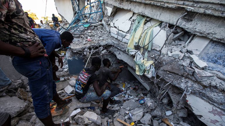 People look for survivors in a house destroyed following the 7.2-magnitude earthquake in Les Cayes, Haiti, on 14 August