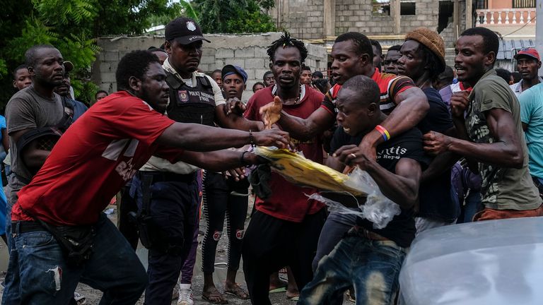 People fight over an envelope with a cash donation left by an employee of former President Michel Martelly in Les Cayes
