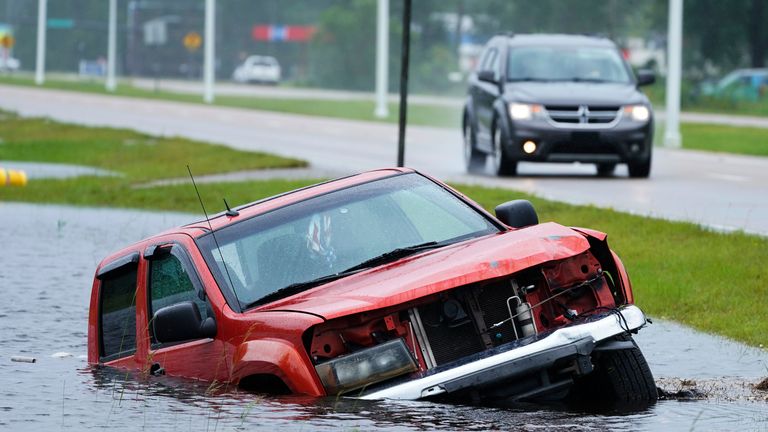An abandoned vehicle is half submerged in a ditch next to a near flooded highway as the outer bands of Hurricane Ida arrive Sunday, Aug. 29, 2021, in Bay Saint Louis, Miss. (AP Photo/Steve Helber)