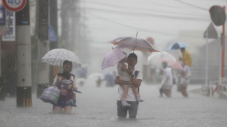 Orang-orang berjalan di jalan yang banjir di Kurume, Prefektur Fukuoka.  Foto: Kyodo / melalui Reuters