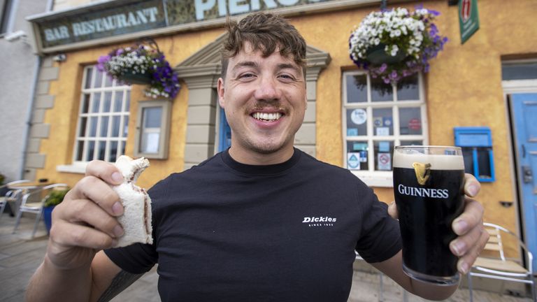 Jordan Leckey holding a celebrity jam sandwich and pint of Guinness outside Pier 36 in Donaghadee after setting a new world record time for swimming from Northern Ireland to Scotland. Picture date: Tuesday August 3, 2021.