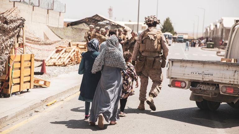 A US Marine escorts a family during an evacuation at Kabul Airport