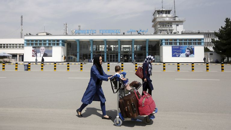 Afghan passengers walk in front of Hamid Karzai International Airport in Kabul