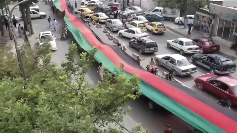 Footage from the Afghan capital shows protesters carrying a long black, red and green flag through the streets.