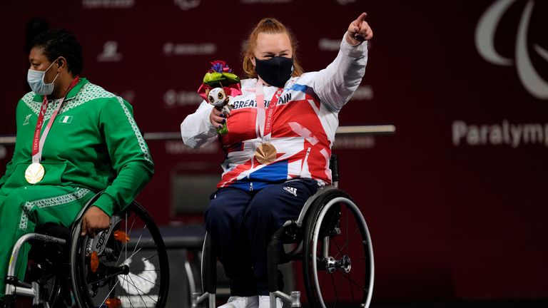 Britain&#39;s Louise Sugden points to students cheering for her after receiving a bronze medal in women&#39;s -86kg powerlifting final at the Tokyo 2020 Paralympic Games, Monday, Aug. 30, 2021, in Tokyo, Japan. (AP Photo/Kiichiro Sato