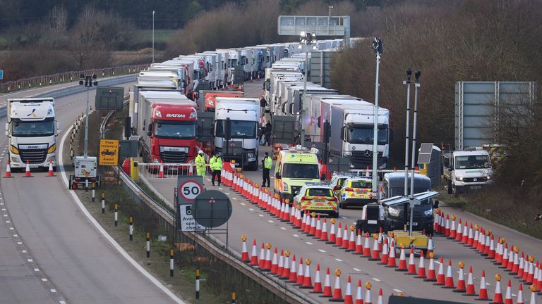 Police vehicles, barriers and road cones mark the front of the line of freight lorries in Operation Brock on the M20 near Ashford in Kent