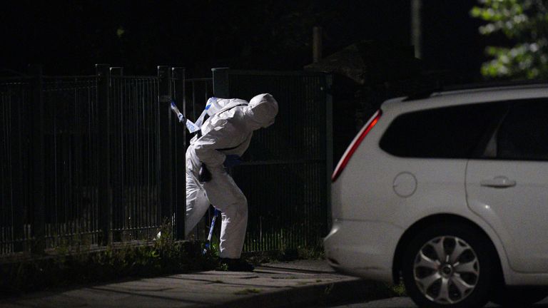 An officer in a forensics suit near the scene of an incident