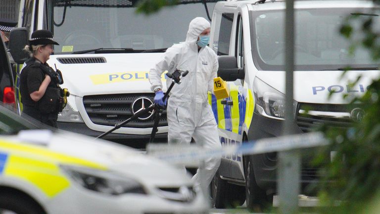 A police investigator carries a tripod and evidence markers in Royal Navy Avenue in the Keyham area of Plymouth