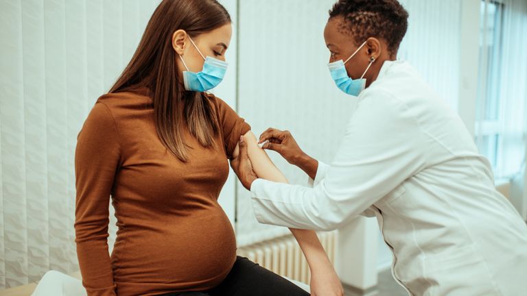 A pregnant woman is vaccinated by a doctor