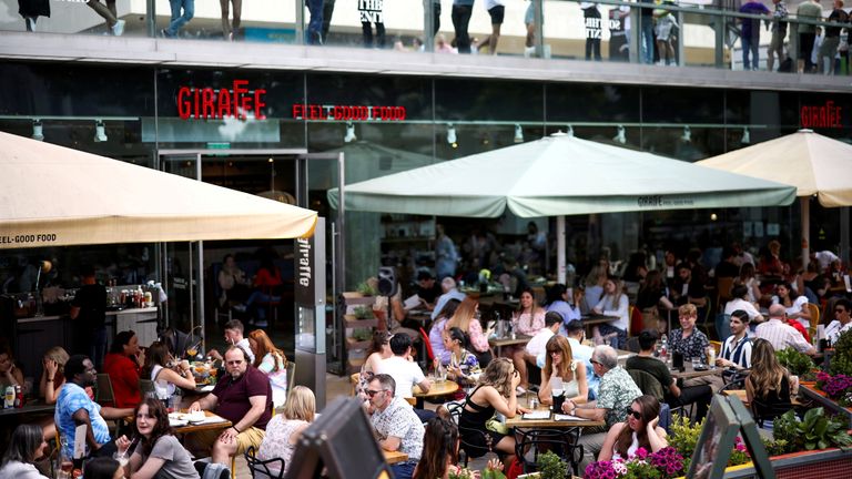People sit at an outdoor restaurant on the South Bank in London