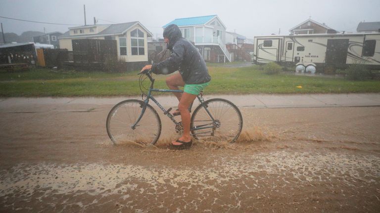 A bicyclist rides through a flooded street as Tropical Storm Henri approaches South Kingstown, Rhode Island