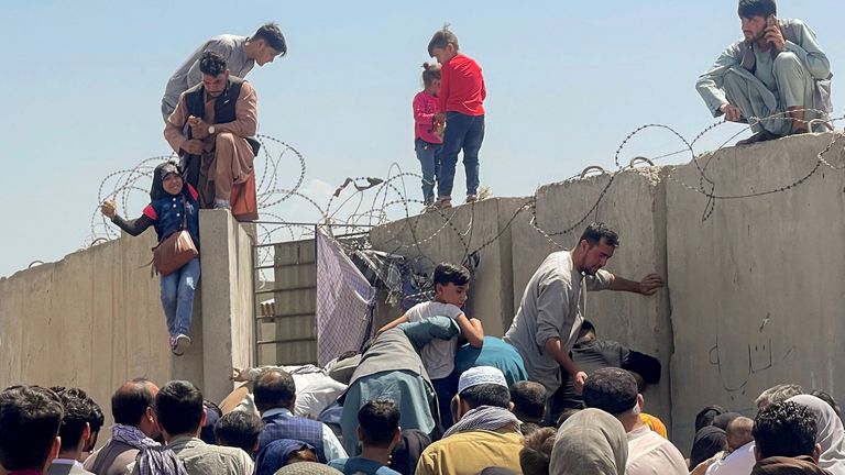 A man pulls a girl up a wall to get inside the Hamid Karzai International Airport in Kabul. 