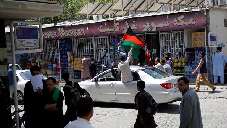Afghans wave their national flag out of a car window in protest on Thursday. Pic: AP