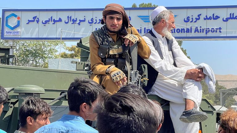 A member of Taliban forces (L) sits on a an armoured vehicle outside Hamid Karzai International Airport in Kabul, Afghanistan August 16, 2021. REUTERS/Stringer NO RESALES. NO ARCHIVES