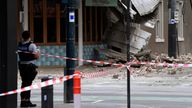 A police officer closes an intersection where debris is scattered in the road after an earthquake damaged a building in Melbourne, Wednesday, Sept. 22, 2021. A magnitude 5.8 earthquake caused damage in the city of Melbourne in an unusually powerful temblor for Australia, Geoscience Australia said. (James Ross/AAP Image via AP)