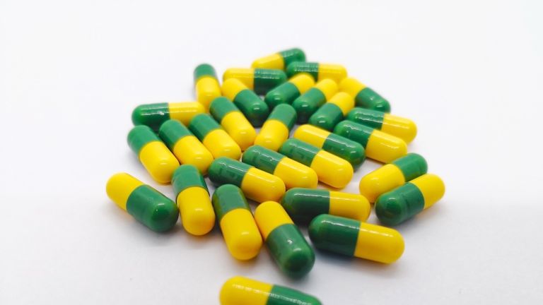 Medication concept. Many green-yellow capsules of Tramadol 50 mg. isolated on white background, narcotic- like pain reliever, used to treat moderate to severe pain.  Selective focus and copy space.