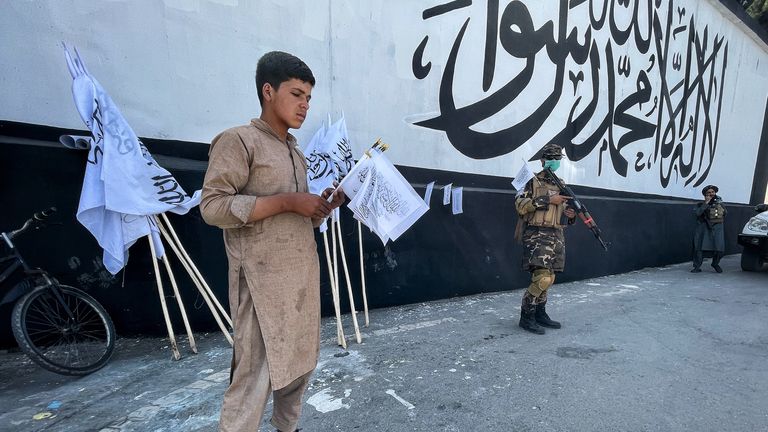 Un jeune garçon vend des drapeaux talibans devant l'ambassade américaine