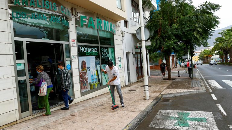 Victor Brito, a pharmacist, cleans the pavement after the eruption of a volcano on the island of La Palma in Los Llanos de Ariadne,  