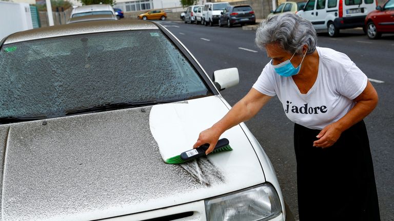 Ana Rodriguez cleans a car after the eruption of a volcano on the island of La Palma in Los Llanos de Ariadne, Spain, on September 22, 2021.  